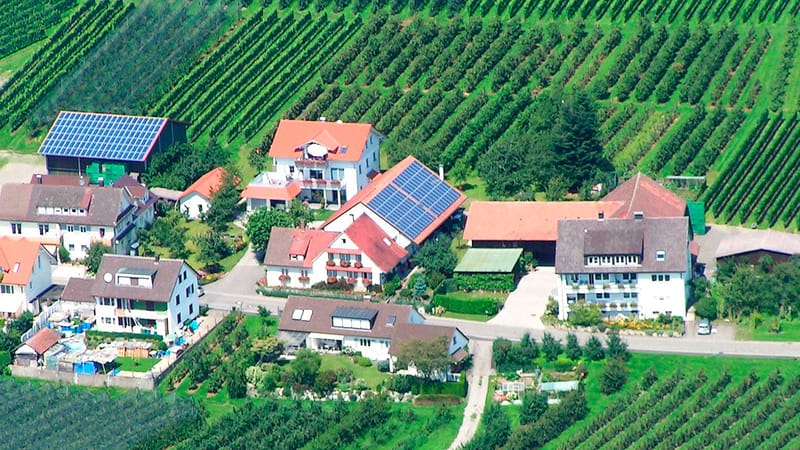 Luftbild des Hofs mit Wohnhäusern und Solarmodulen, rundherum Obstanlagen