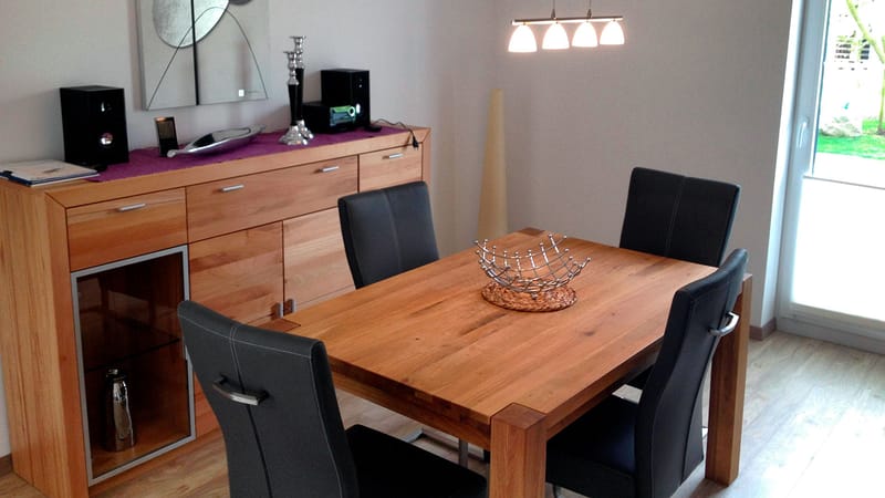 Essbereich mit Holztisch, vier dunklen Stühlen und Sideboard