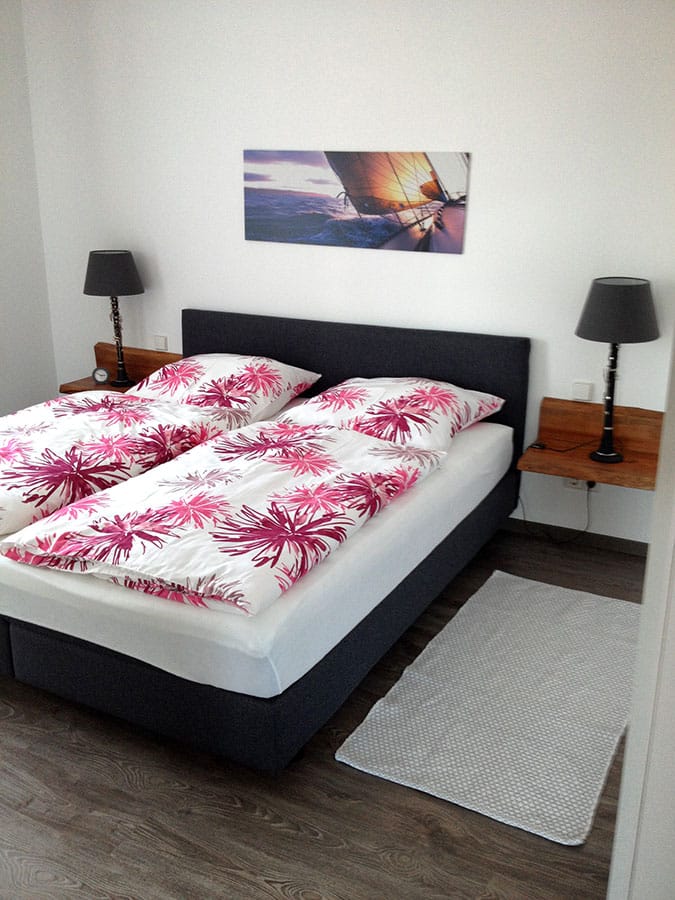 Schlafzimmer mit Doppelbett und pink gemusterter Bettwäsche (Hochformat)